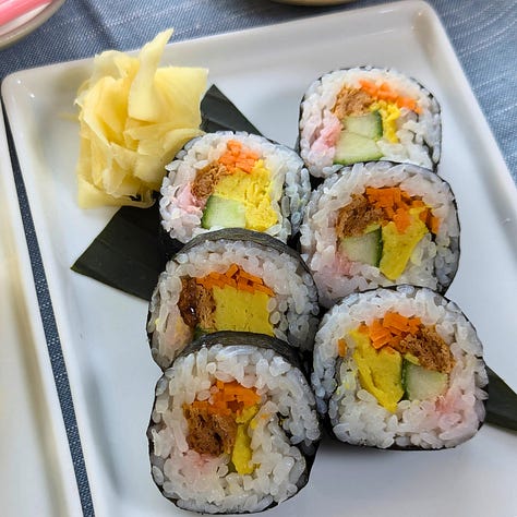 An assortment of futomaki sushi rolls, each filled with a variety of colorful ingredients like vegetables, pickled items, and vegan tamagoyaki. 