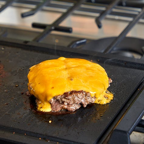 burgers on a grill, burger patty topped with cheese, assembled burger