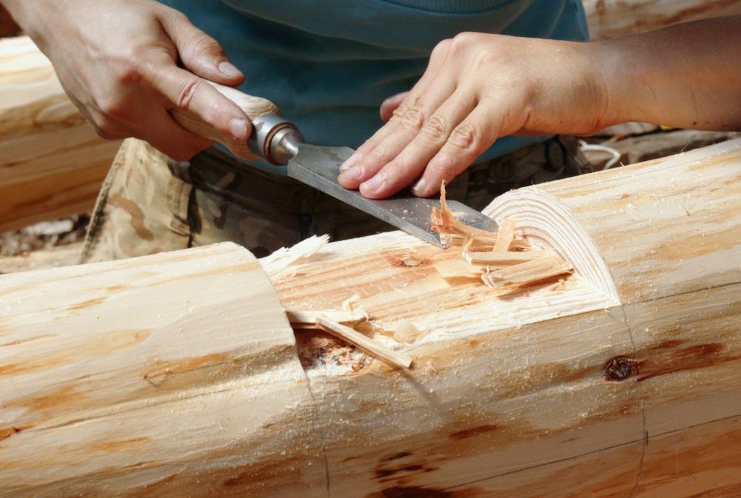 a person cutting a piece of wood with a knife