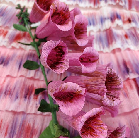 Pink paper foxglove, a handful of foxglove florets, a finished paper foxglove with pink and purple painterly florets.
