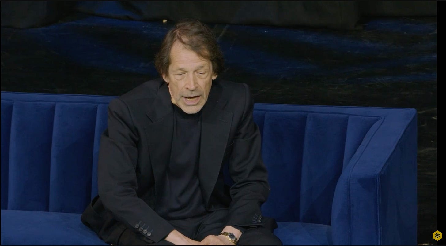 Video still of Peter Saville on the A&AD Youtube channel showing a man sitting on a stage about to speak