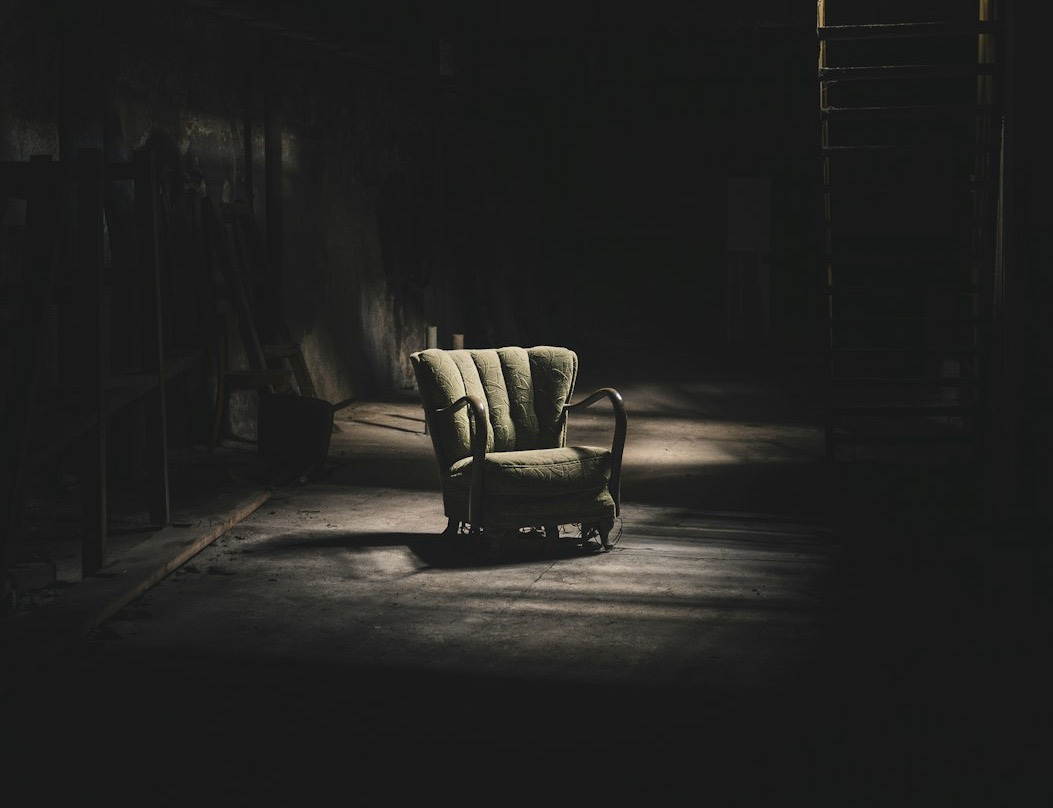 a dark room with a chair and a ladder
