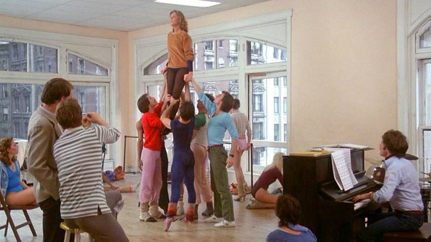 Lauren Bacall held aloft by a group of dancers in a studio