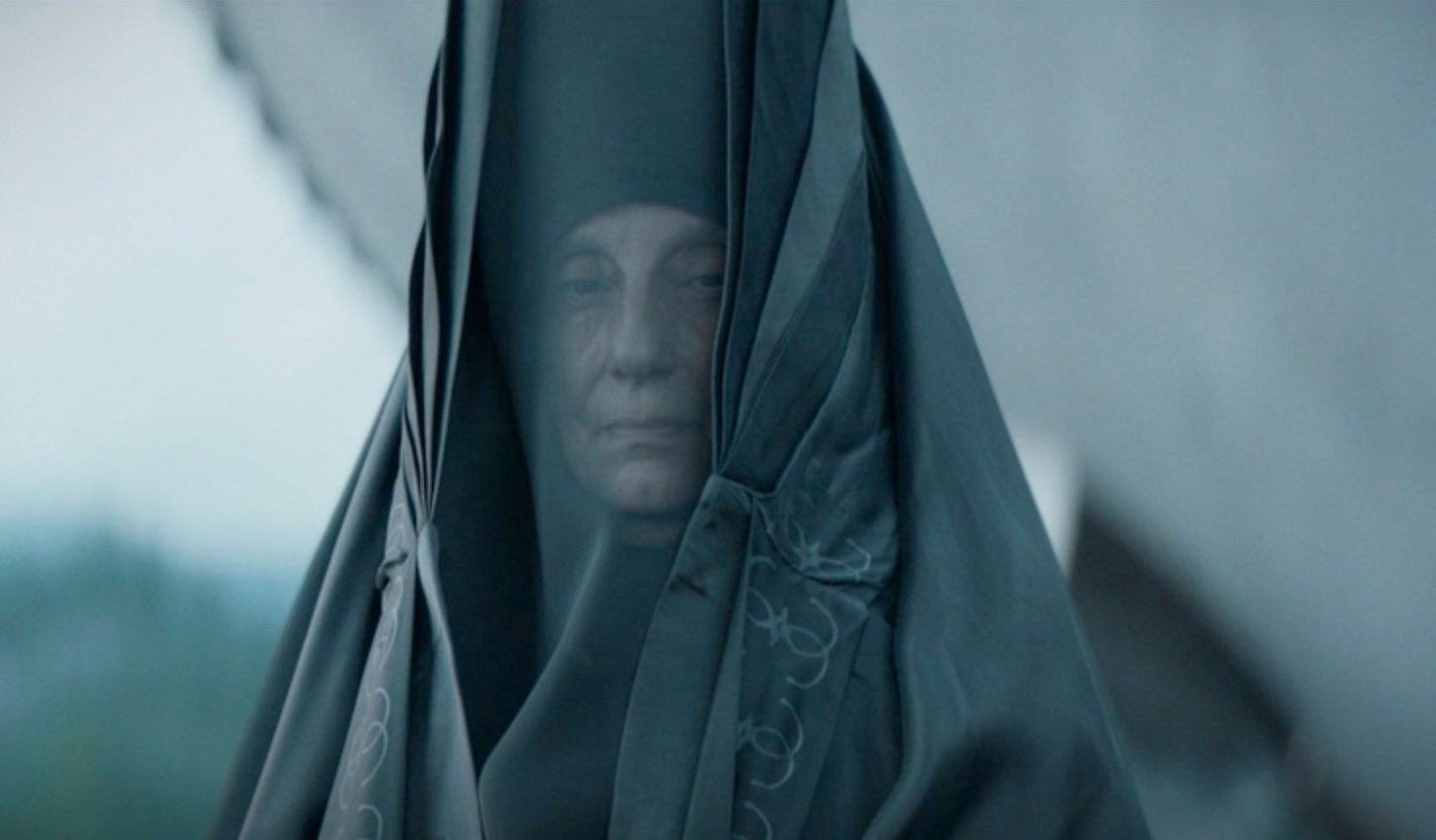 A Bene Gesserit priestess, in elaborately worked black costume with a dark veil and a very tall hat