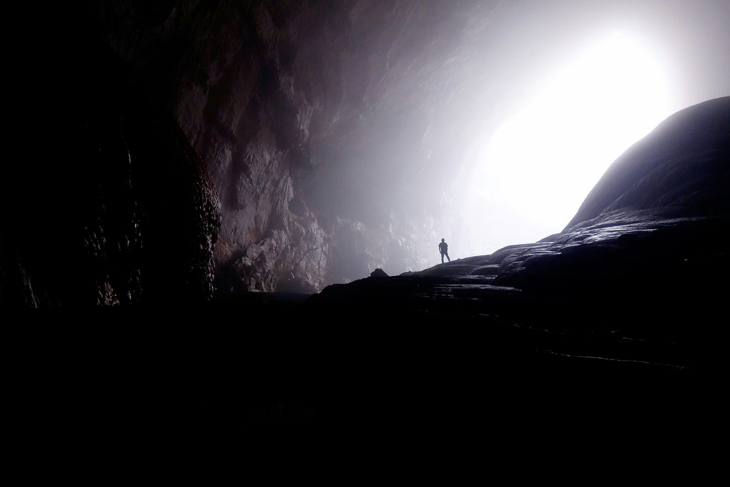 The silohuette of a man in a large cavern opening
