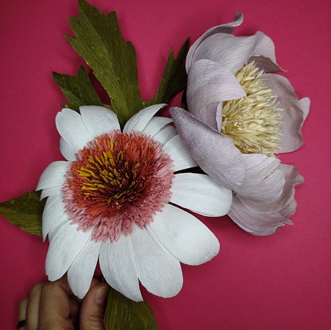 Artistic flowers made of paper, blue cornflowers, lilac peony and purple lavender, all coloured using red cabbage.