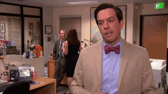 a man in a suit and bow tie is standing in an office