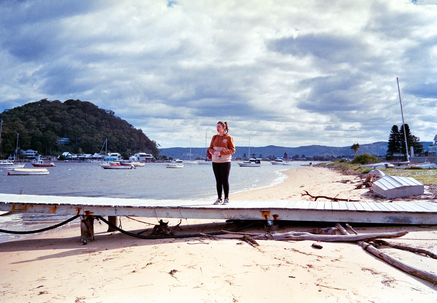 Josie standing on the middle of a boat ramp on a beach, the sun shining brightly on her while the boats surround her in the background on the harbor. Josie standing on the middle of a boat ramp on a beach, the sun shining brightly on her while the boats surround her in the background on the harbor.