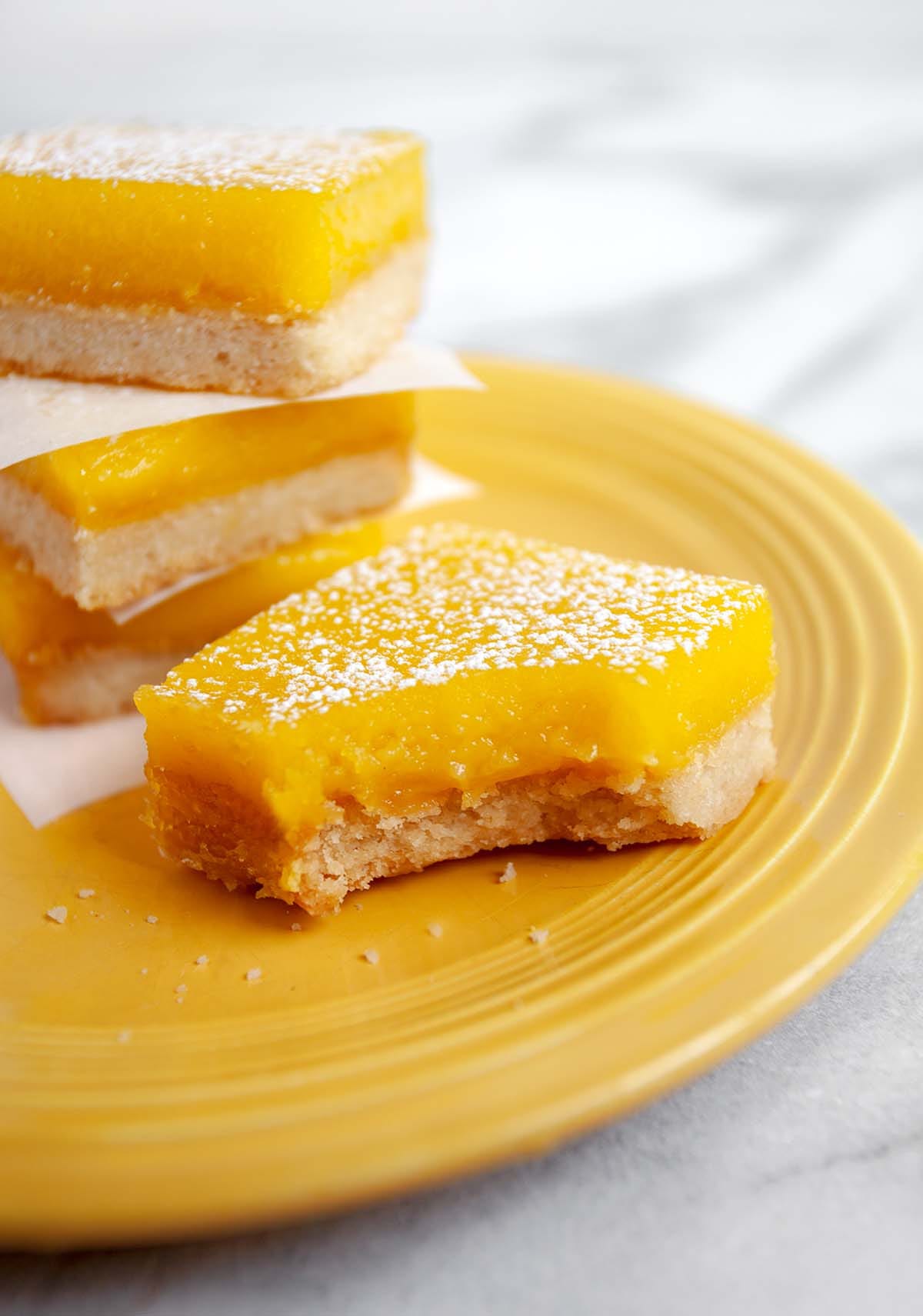 Traditional square lemon bars with a thick, buttery shortbread crust and a bright yellow citrus custard topped with powdered sugar.