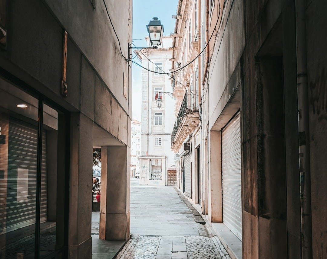 brown brick pathway between brown brick buildings during daytime brown brick pathway between brown brick buildings during daytime