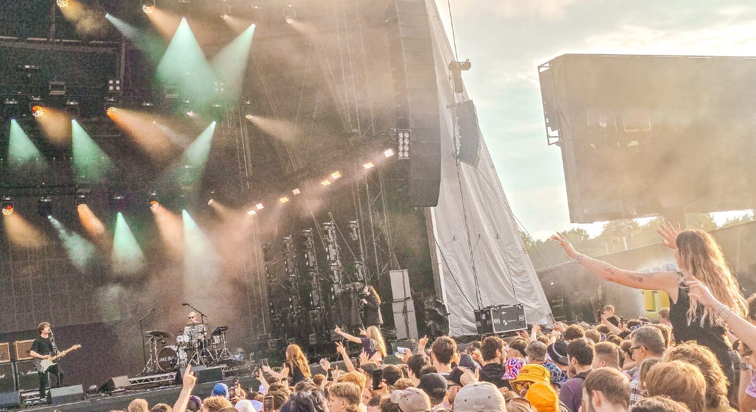 Jake Bugg on stage with green and orange lights, with a large crowd in front of him