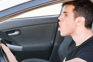 Handsome Young Man driving his car, pressing horn while in a traffic jam
