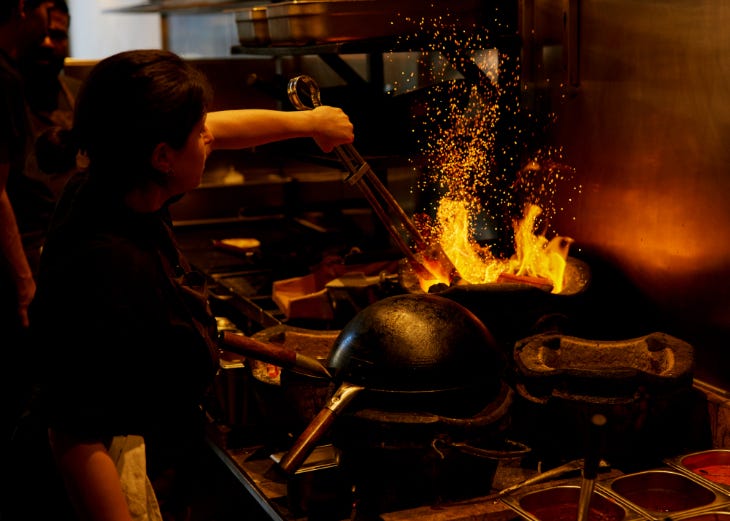 Things to do in London today: a chef cooking in a wok over live fire Things to do in London today: a chef cooking in a wok over live fire