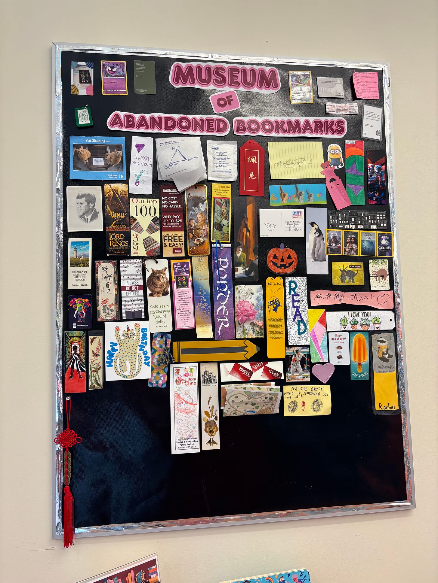 black bulletin board with bookmarks pinned on it, titled the Museum of Abandoned Bookmarks