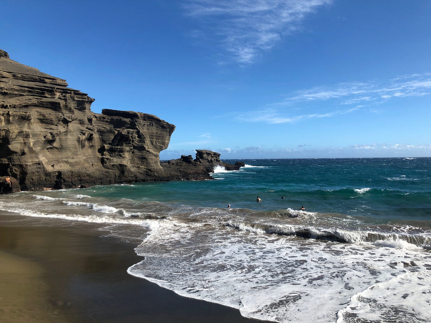 A secluded beach with blue green water and olive colored sand