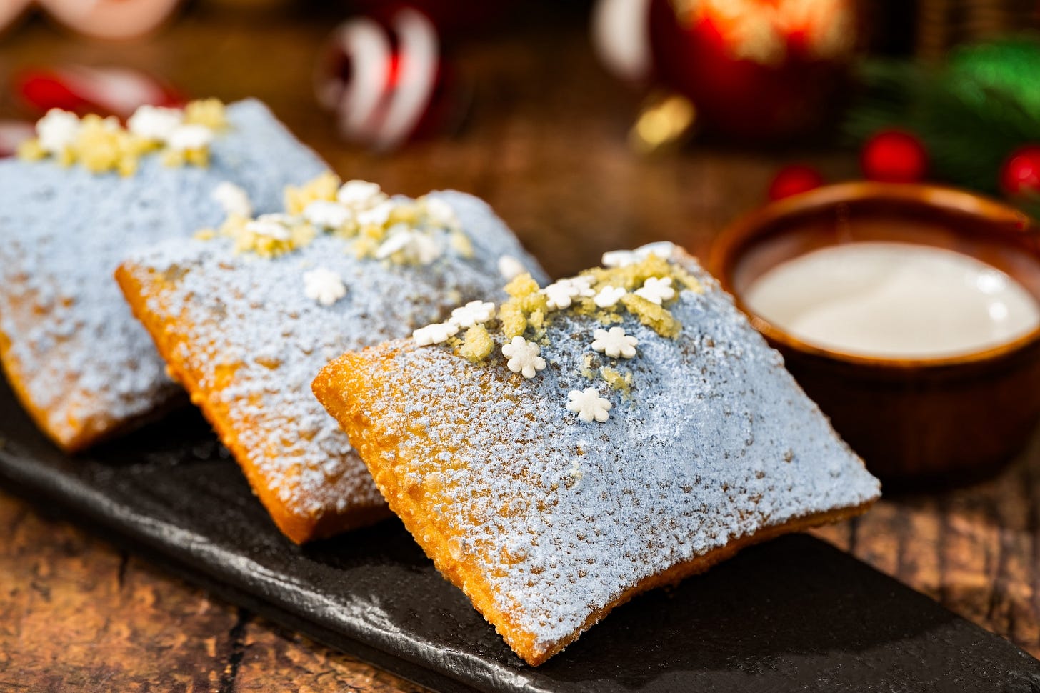 Festive Beignets: Light and fluffy beignets dusted with blue sugar cookie dust and served with cookie butter icing