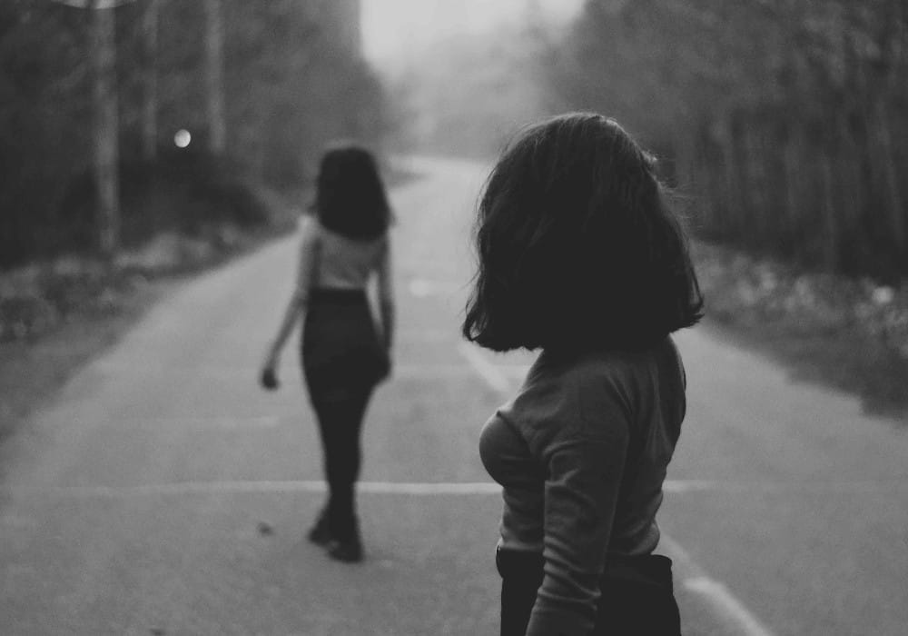 Polyamorous lesbian couple with one girl walking away and the other staring after her