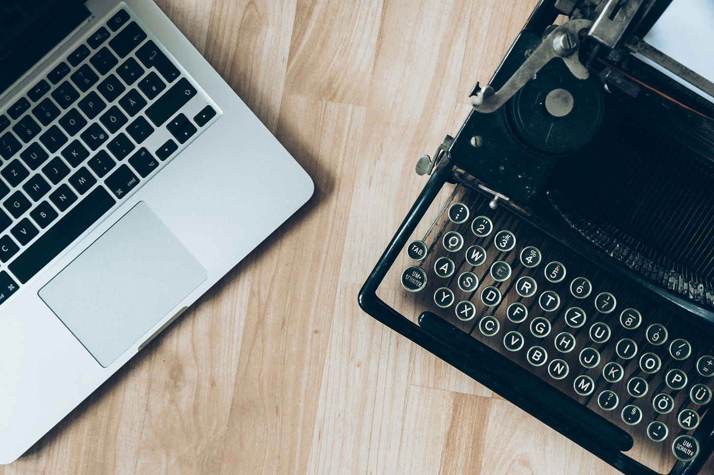 Photo of a silver laptop alongside a black vintage typewriter