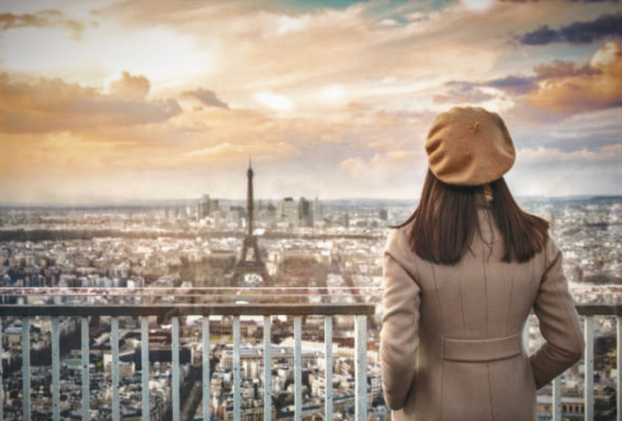 Expat woman living abroad gazing out over city of Paris, France, reflecting on identity and transformation while living overseas.