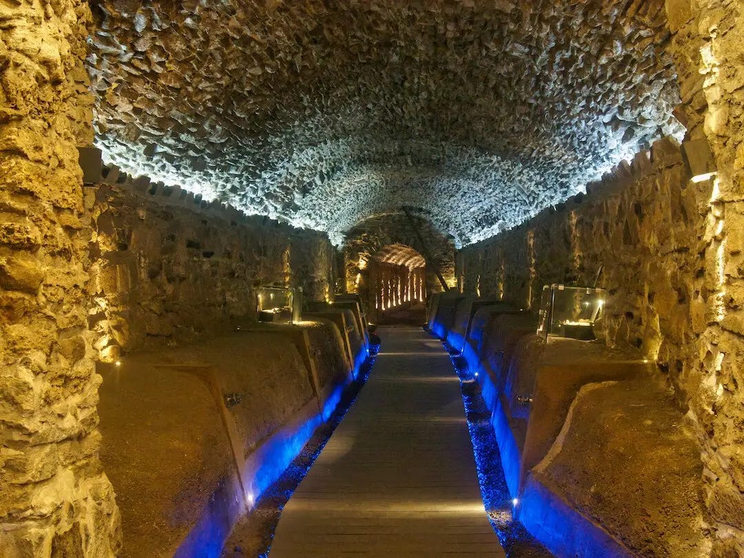 An underground stone tunnel illuminated with blue light to show the pathway