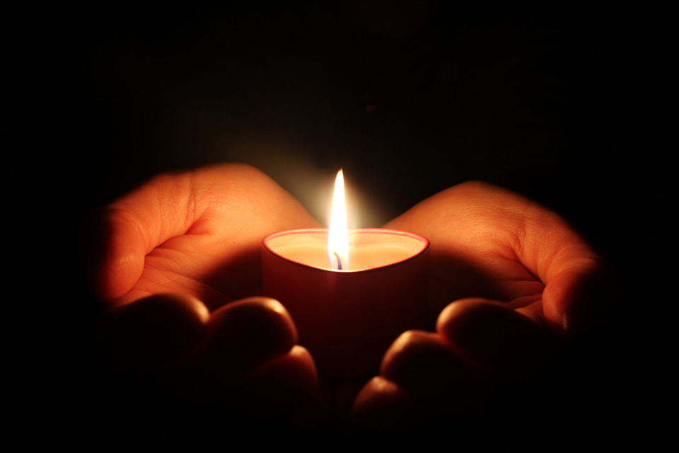A candle held by two hands in the darkness A candle held by two hands in the darkness