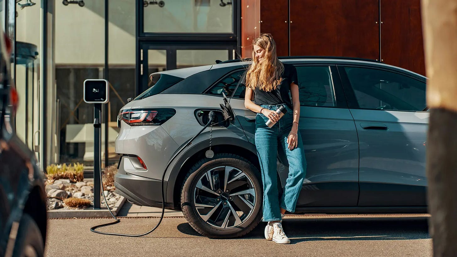 Chica recargando batería de su coche en punto de recarga eléctrico Chica recargando batería de su coche en punto de recarga eléctrico