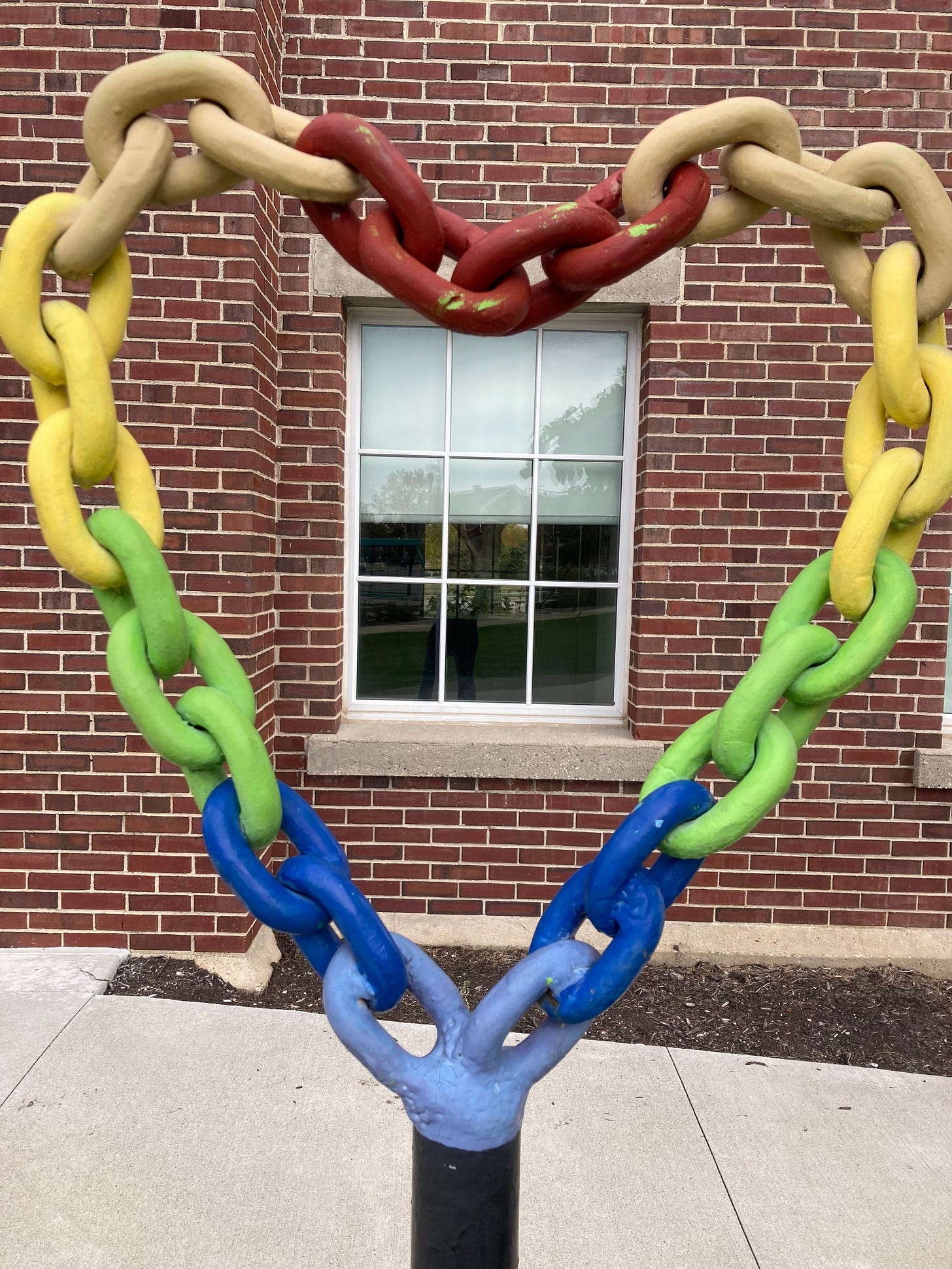 All Means All: picture of a metal heart made out of a chain in rainbow colors