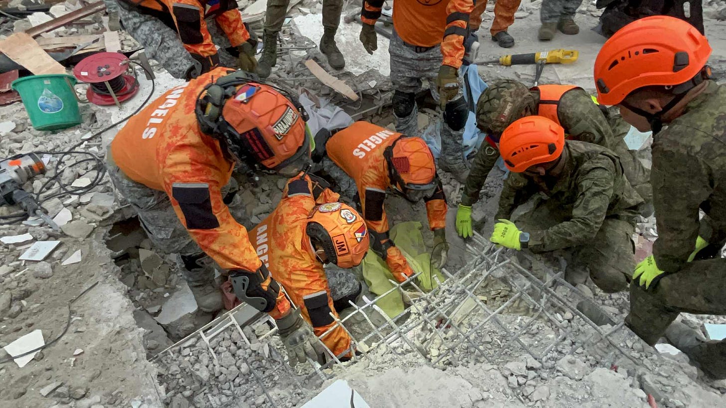 Rescue workers in orange and green uniforms with helmets carefully pulling a survivor from collapsed concrete and metal debris after an earthquake in the Philippines. Rescue workers in orange and green uniforms with helmets carefully pulling a survivor from collapsed concrete and metal debris after an earthquake in the Philippines.
