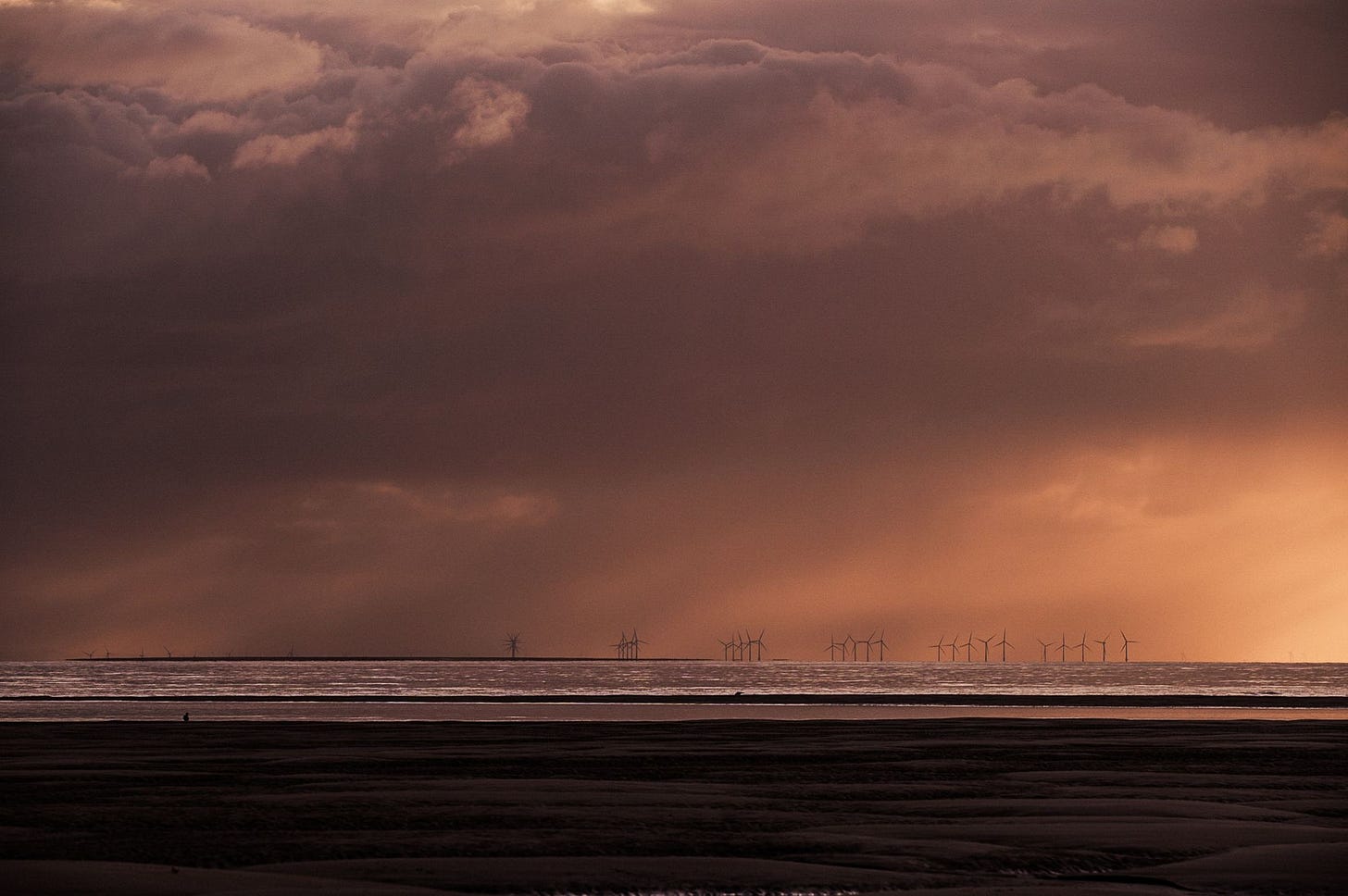 Wind turbines on the horizon with storm clouds over head.