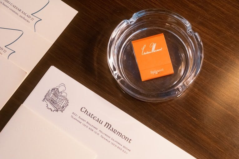 A matchbook reading "Chateau Marmont" rests inside an ashtray. To the left of the ashtray is stationary with the Chateau's letterhead. A matchbook reading "Chateau Marmont" rests inside an ashtray. To the left of the ashtray is stationary with the Chateau's letterhead.