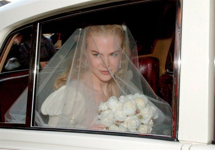 This may contain: a woman in a white wedding dress and veil is sitting in a car with flowers