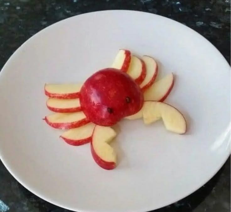 This may contain: an apple shaped like a crab on a white plate