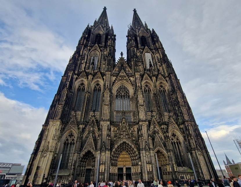 Front view of the cathedral in cologne - two towers. many people in front of it. 