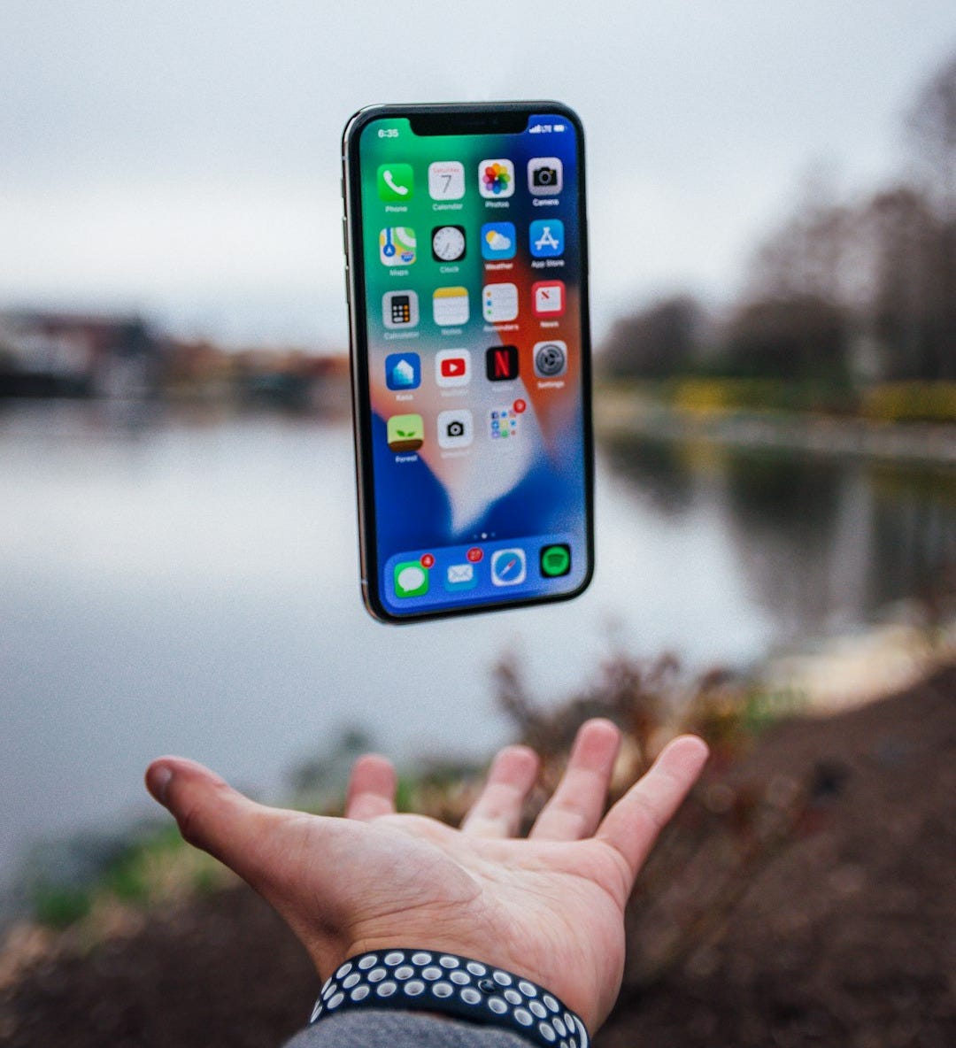 silver iPhone X floating over open palm