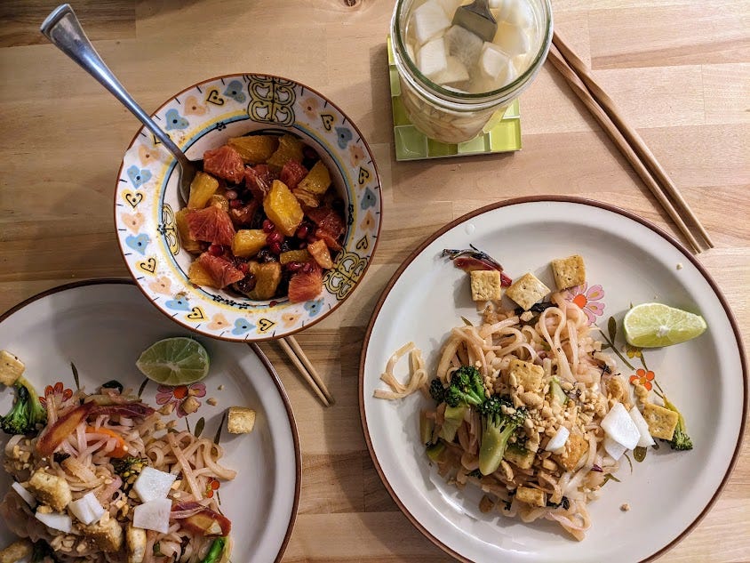 plates of pad thai and orange salad