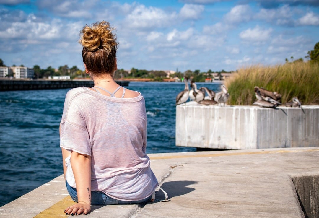 woman wearing grey shirt sitting on grey concrete surface