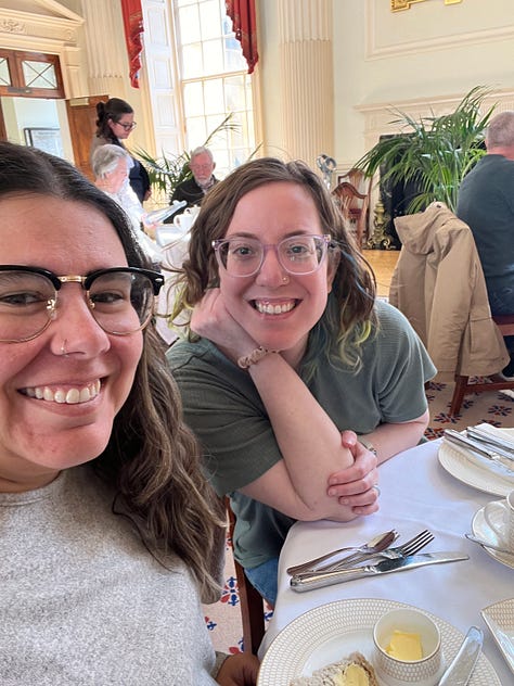 photos of Katie on vacation in London with Chris, seeing Les Mis, kissing in Bath, drinking tea, eating gluten free fish and chips, seeing a statue from DDLJ, and freezing at a football match.
