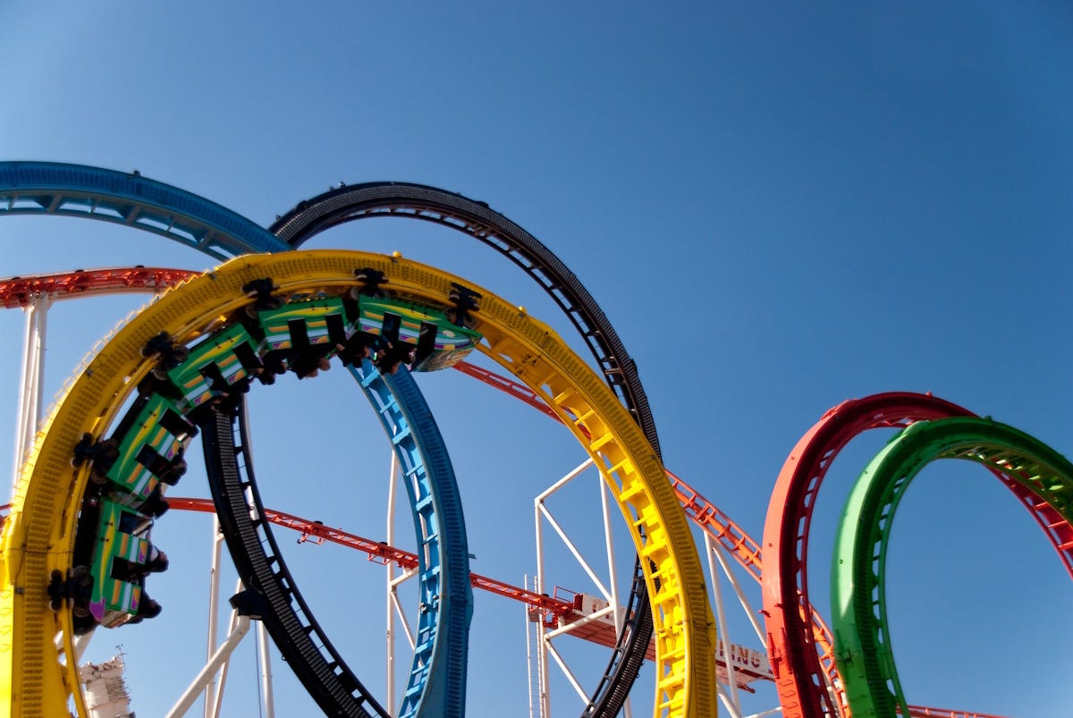 Multi-colored rollercoaster against bright blue sky Multi-colored rollercoaster against bright blue sky