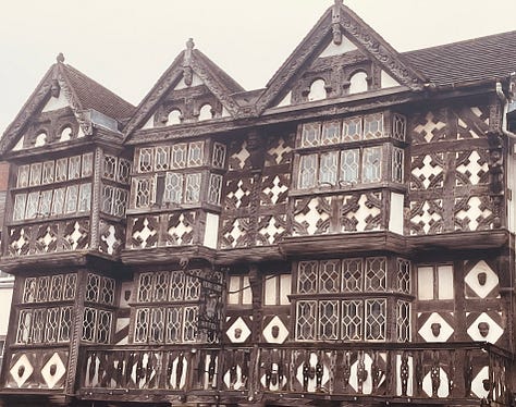 A tower rises through fog with yellow machines in front; spooky branches; a black and white timbered building