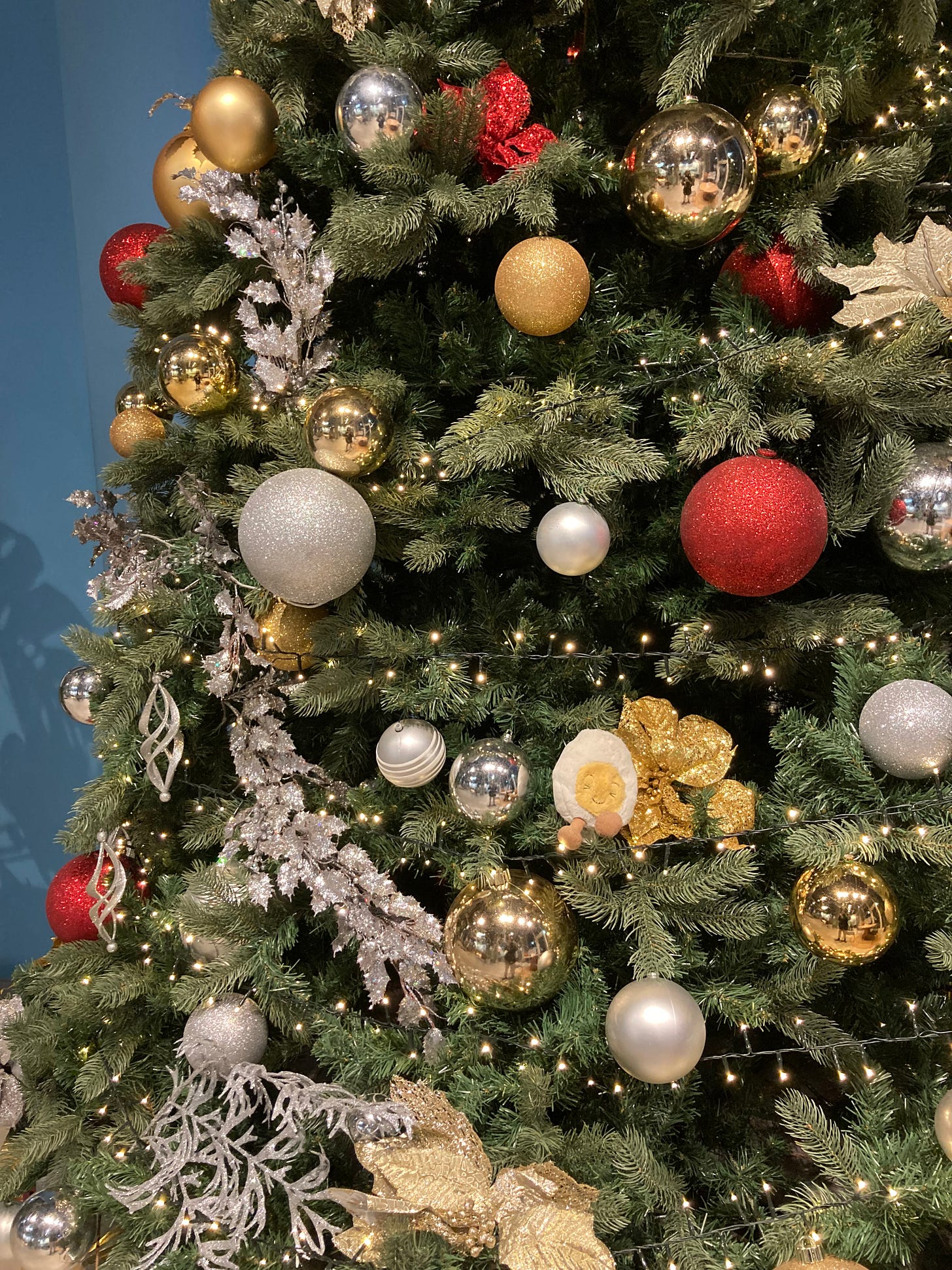 Dippy the soft toy egg nestled in a giant Christmas tree among the baubles and tinsel