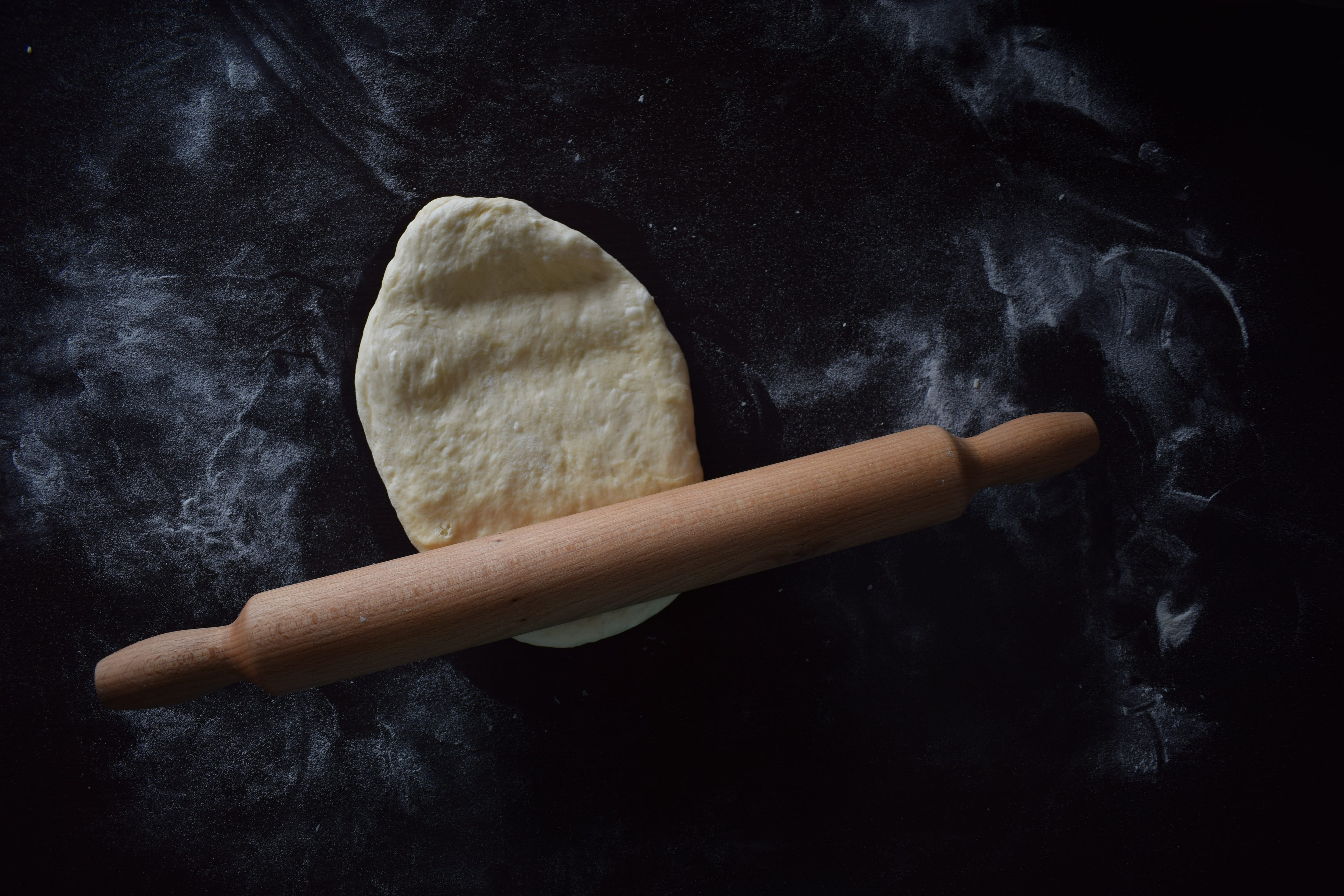 Dough partially flattened under a rolling pin. Dough partially flattened under a rolling pin.