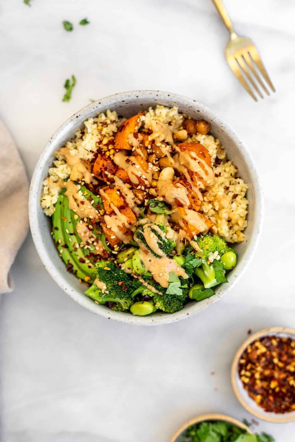 One buddha bowl with sweet potatoes and broccoli with a fork on the side. One buddha bowl with sweet potatoes and broccoli with a fork on the side.