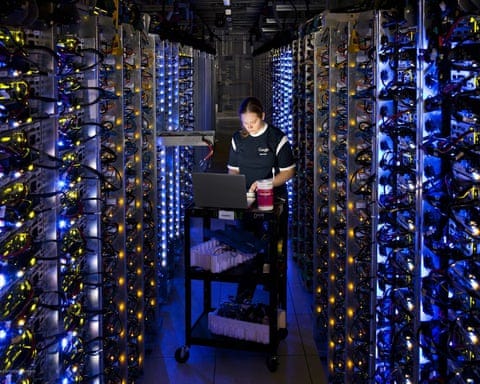 A Google worker monitors equipment while sandwiched between racks of computer servers A Google worker monitors equipment while sandwiched between racks of computer servers