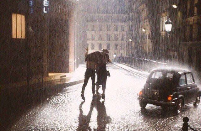 This may contain: two people walking in the rain with an umbrella This may contain: two people walking in the rain with an umbrella