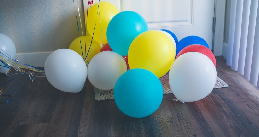 assorted-color balloons on floor near closed door assorted-color balloons on floor near closed door