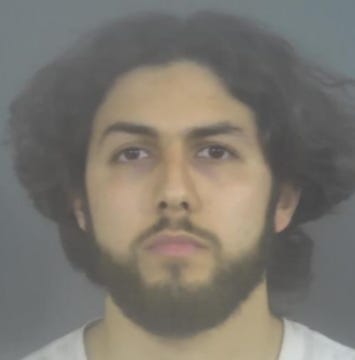 First image shows a young man with curly dark hair, wearing clear-framed glasses, a white dress shirt, red striped tie, and dark suit jacket, smiling slightly outdoors with green foliage and a blurred background. Second image depicts the same man with long dark wavy hair and beard, neutral expression, against a plain gray background resembling a mugshot or ID photo.