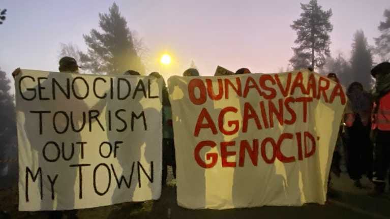 Mielenosoittajat pitävät iskulauselakanoita tiesulun muodossa Ounasvaaralla Rovaniemellä.