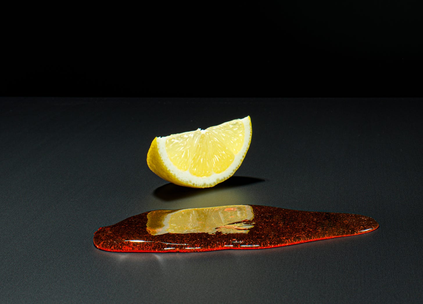 Viscous red liquid or gel of some kind in front of a lemon slice.  Some arty thing,doesn't look to have happened naturally