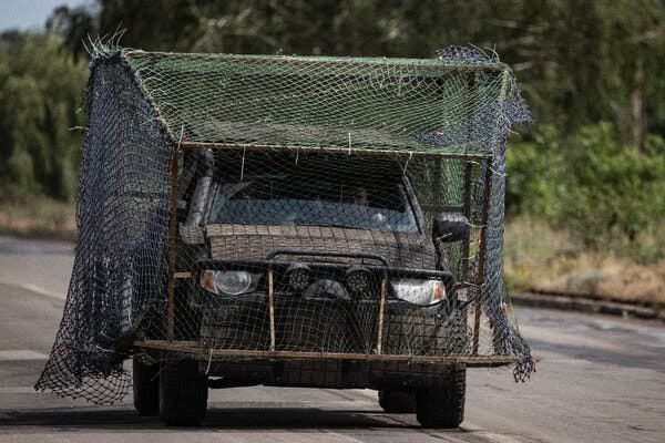 A military truck covered in nets.