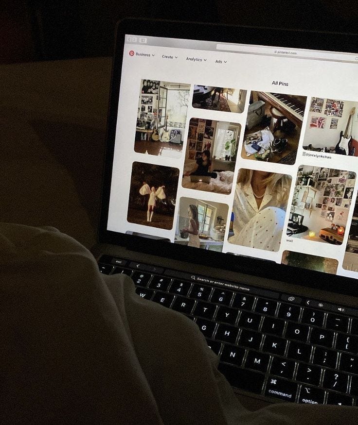 This may contain: an open laptop computer sitting on top of a bed next to a person's lap